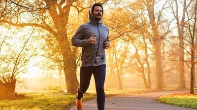A man running through the park at sunrise.